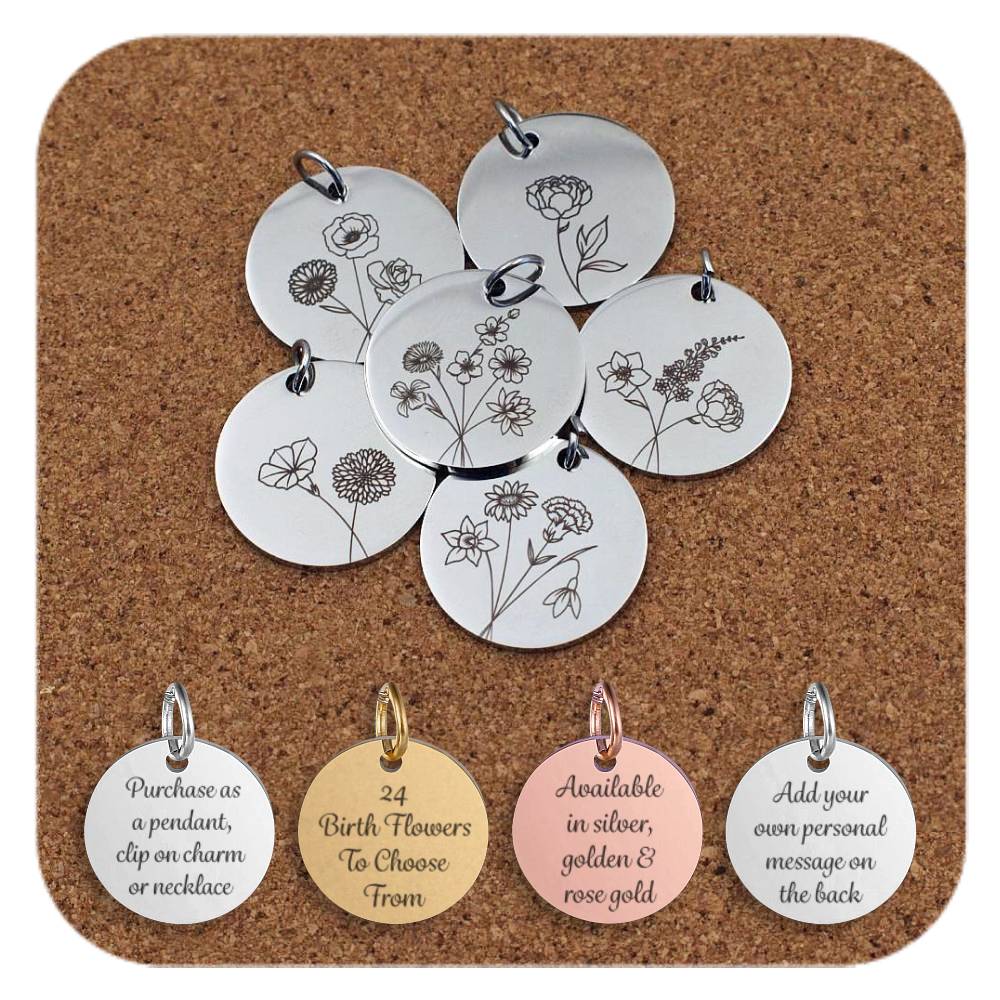 Collection of round metal pendants engraved with different flower designs, displayed on a cork board. Each pendant features a unique floral illustration representing various flowers in detailed line art style. Below the pendants are four additional discs in silver, gold, and rose gold finishes, engraved with the text: 'Purchase as a pendant, clip on charm or necklace,' '24 Birth Flowers To Choose From,' 'Available in silver, golden & rose gold,' and 'Add your own personal message on the back.'