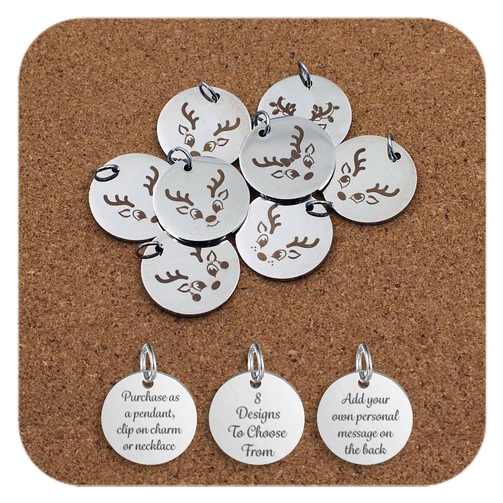 Set of round silver metal pendants engraved with cute reindeer face designs, displayed on a cork board. Each pendant features a cartoon-style reindeer with antlers and a different expressions. Beneath the pendants are three discs engraved with the text: 'Purchase as a pendant, clip on charm or necklace,' '8 Designs To Choose From,' and 'Add your own personal message on the back.'