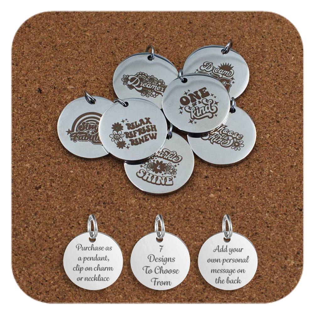 Round stainless steel pendants engraved with positive retro-style messages like ‘Relax Refresh Renew,’ ‘One of a Kind,’ and ‘Shine.’ displayed on cork. . Below the pendants are three additional discs showing engraved text that reads: 'Purchase as a pendant, clip on charm or necklace,' '7 Designs To Choose From,' and 'Add your own personal message on the back'