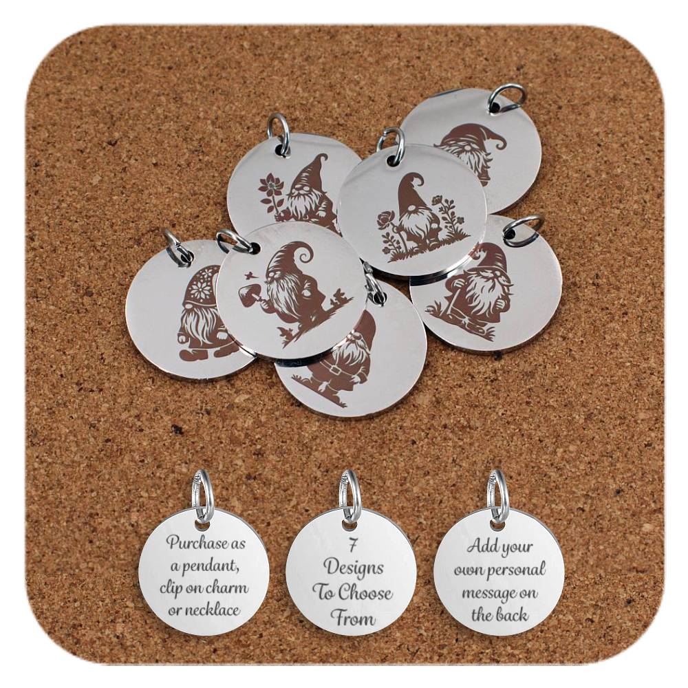 Collection of round silver metal pendants with engraved gnome designs, displayed on a cork board. Each pendant features a unique gnome illustration with different poses and accessories such as mushrooms, flowers, and hats. Below the pendants are three additional discs showing engraved text that reads: 'Purchase as a pendant, clip on charm or necklace,' '7 Designs To Choose From,' and 'Add your own personal message on the back.'