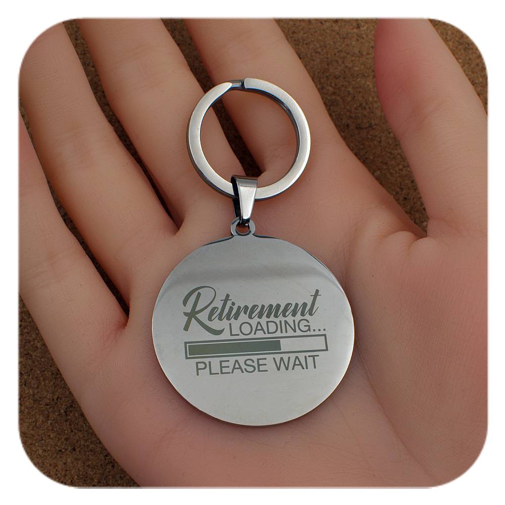Keychain with 'Retirement Loading... Please Wait' text held in a hand.