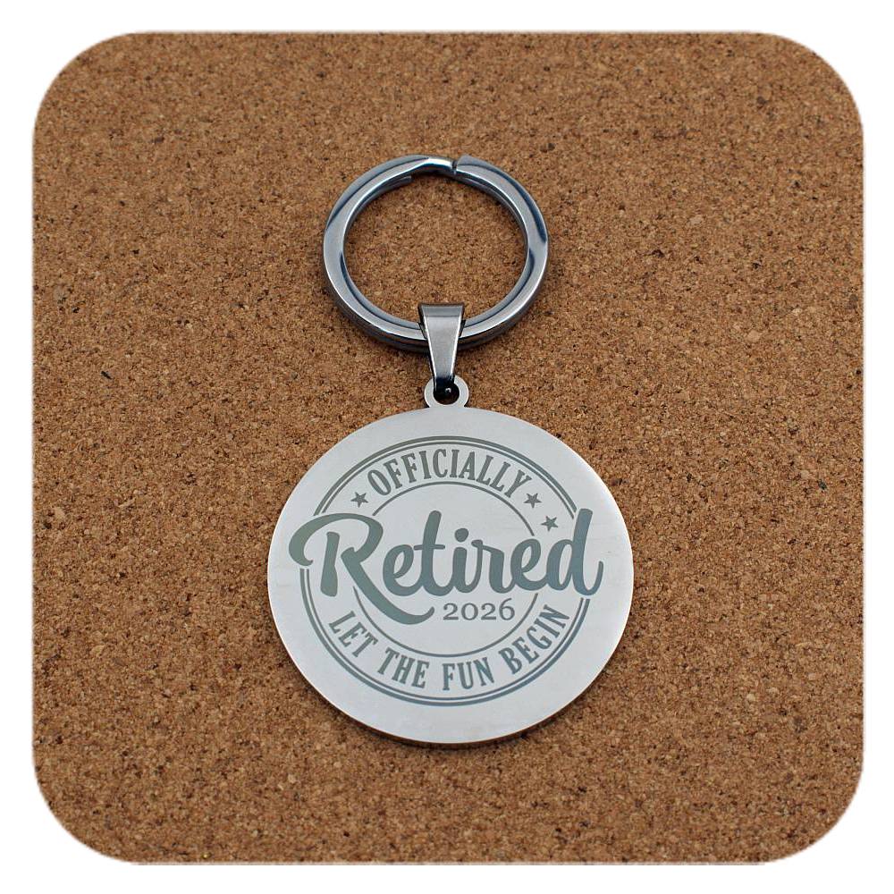 Keychain with 'Officially Retired 2026' text on a cork background