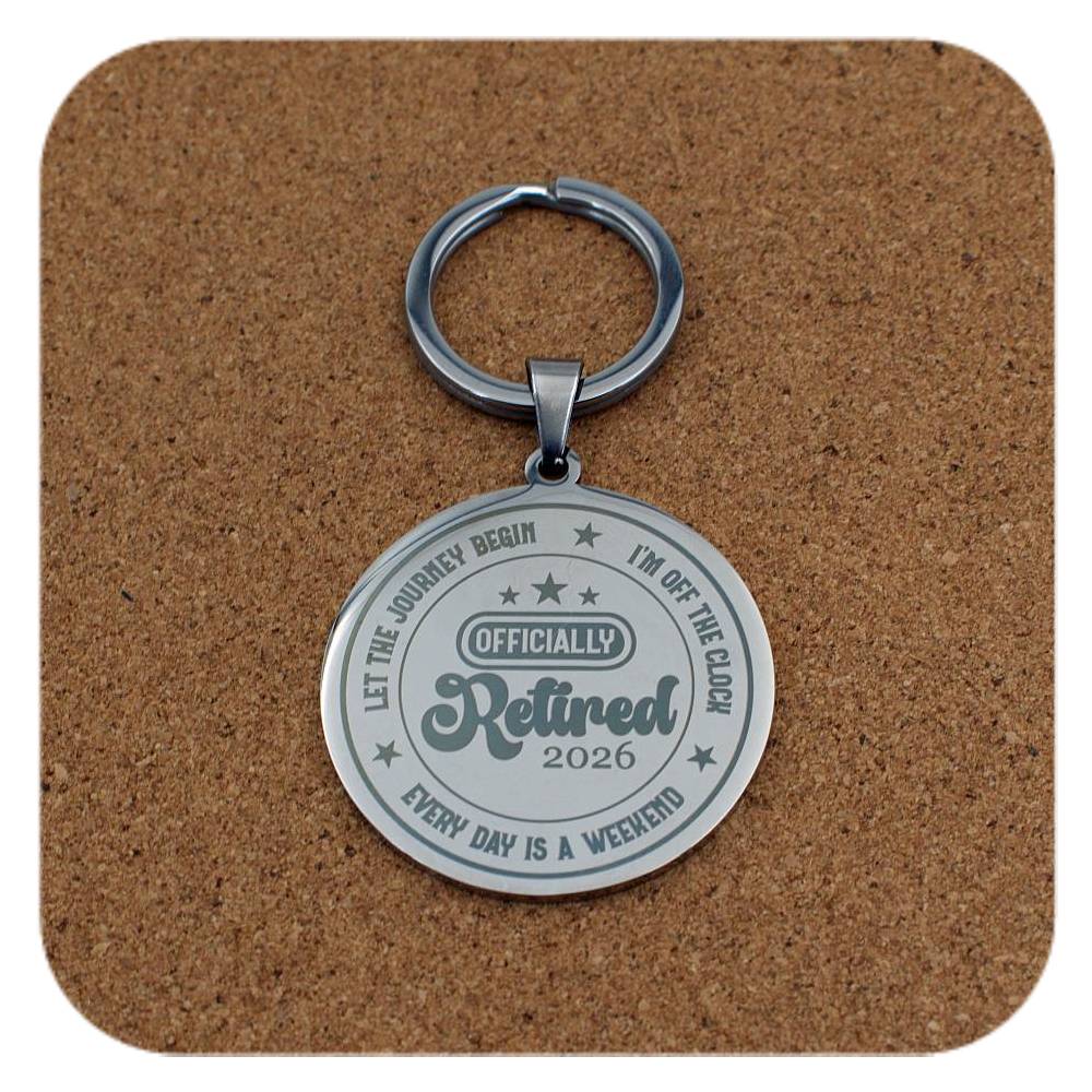 Keychain with 'Officially Retired 2026' text on a cork background