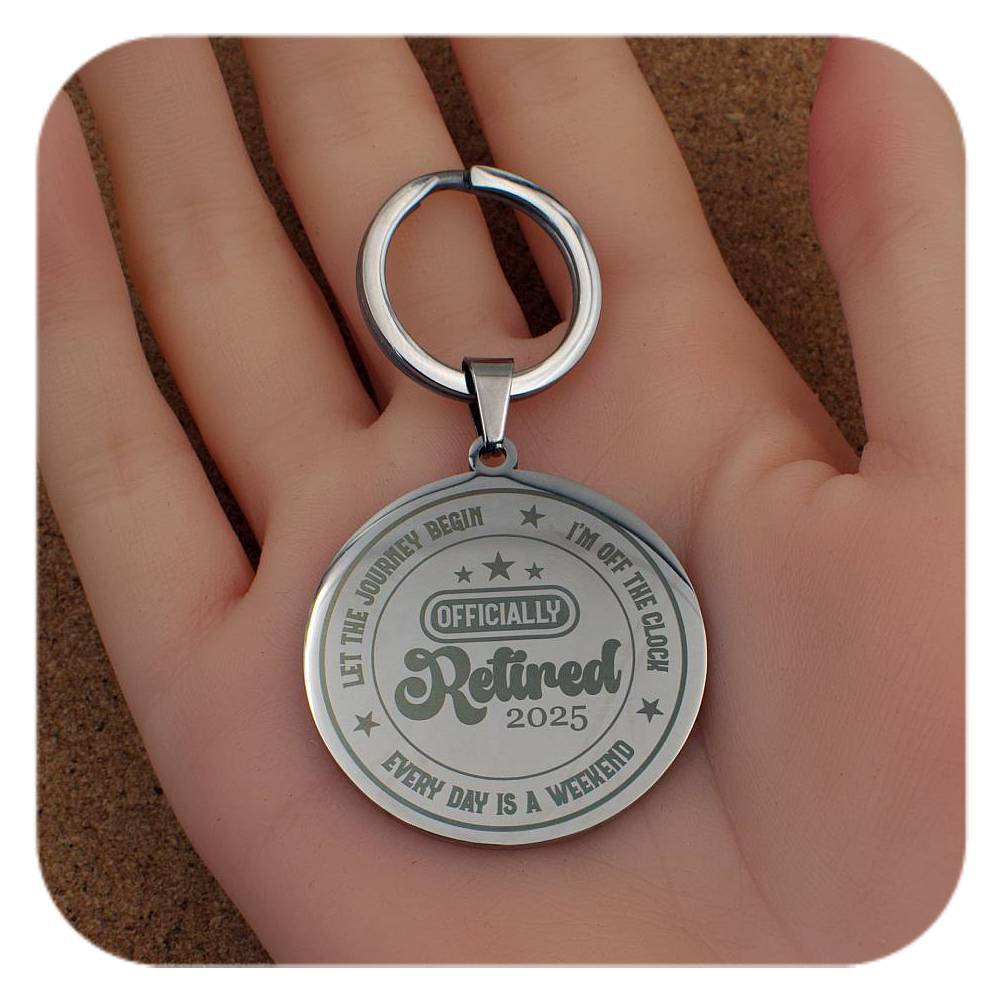 Silver retired keychain held in a hand on a brown surface