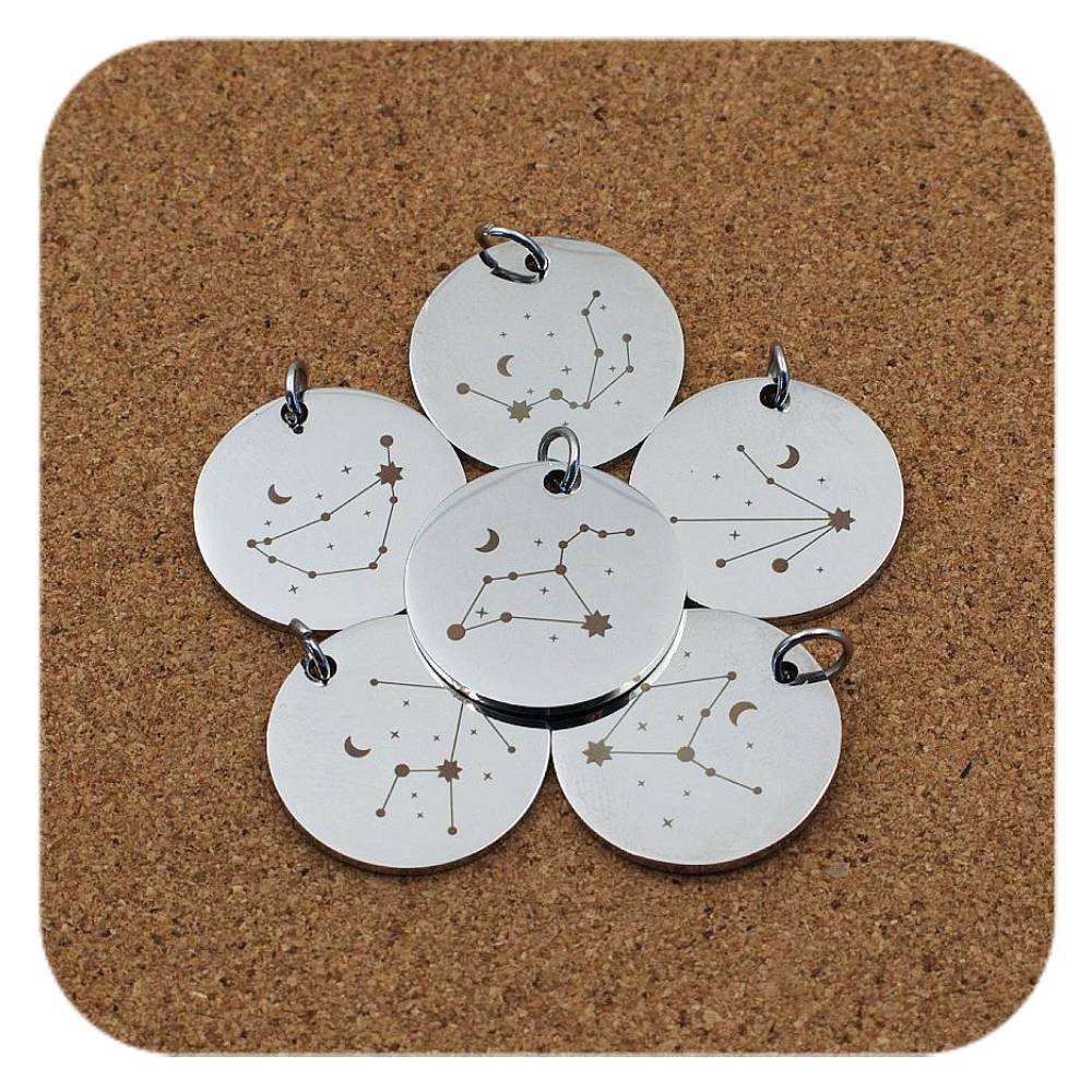 Silver pendants with different Celestial Star Sign designs on cork background