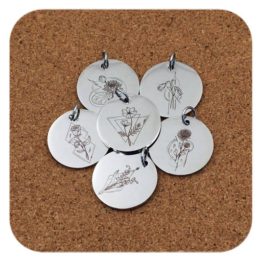Silver pendants with different Geometric Birth Flower designs on cork background