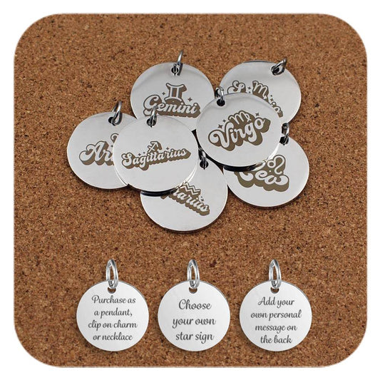 A set of stainless steel round pendants engraved with zodiac star sign names in decorative fonts, including Aries, Gemini, Virgo, Sagittarius, and more, arranged on a cork background. Below the pendants are three additional discs showing engraved text that reads: 'Purchase as a pendant, clip on charm or necklace,' 'Choose your own star sign,' and 'Add your own personal message on the back'