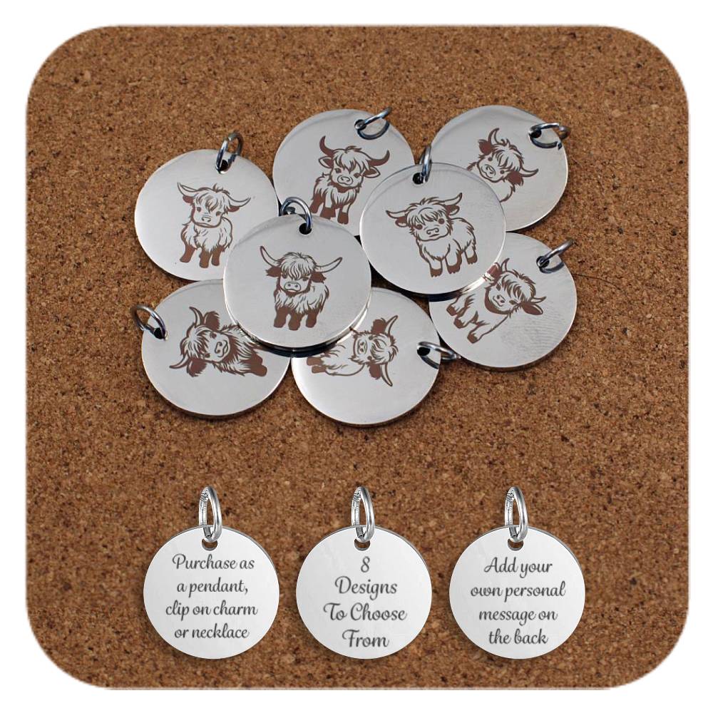 Selection of round silver metal pendants engraved with various Highland cow designs, displayed on a cork board. Each pendant features a different illustration of a Highland cow in various poses and expressions, with detailed horns and shaggy hair. Below the pendants are three additional discs engraved with the text: 'Purchase as a pendant, clip on charm or necklace,' '8 Designs To Choose From,' and 'Add your own personal message on the back.'