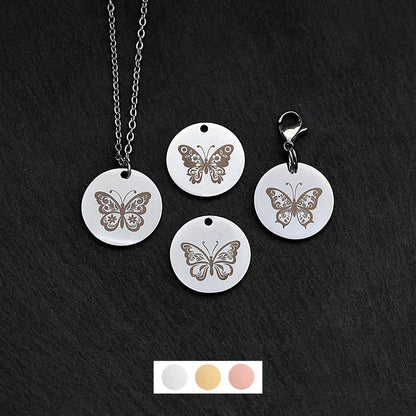 Four silver round disc pendants on a black slate background showing four different butterfly designs. One has a silver necklace attached by a jump ring and another has a lobster clasp and split ring attached to it