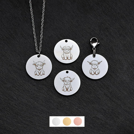 Four silver round disc pendants on a black slate background showing four different highland cow designs. One has a silver necklace attached by a jump ring and another has a lobster clasp and split ring attached to it