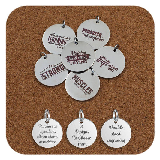 Engraved stainless steel pendants displayed on corkboard, each featuring motivational and witty phrases like 'Mistakes mean you're trying', 'Stay strong', 'Muscles are optional', 'Progress not perfection', and 'Even WiFi has bad days'. Bottom row shows pendants reading: 'Purchase as a pendant, clip on charm or necklace', '3 Designs To Choose From', and 'Double sided engraving'.