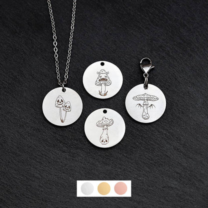 Four silver round disc pendants on a black slate background showing four different creepy mushroom toadstool designs. One has a silver necklace attached by a jump ring and another has a lobster clasp and split ring attached to it