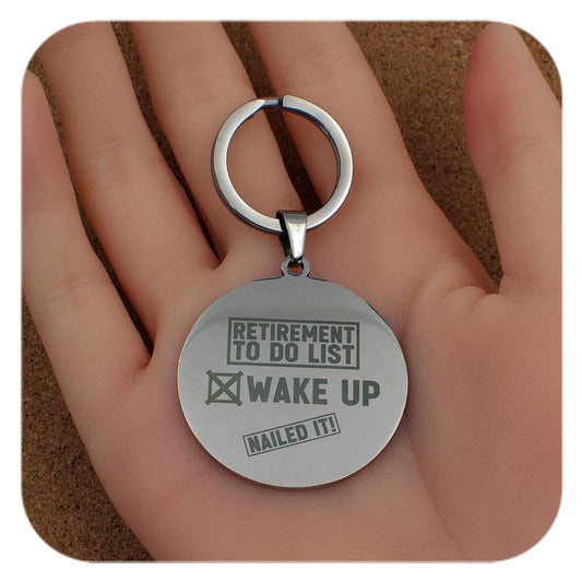 Silver keyring with Retirement To Do List design held in a hand