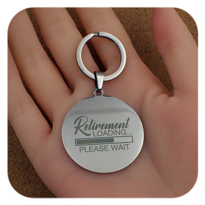 Keychain with 'Retirement Loading... Please Wait' text held in a hand.