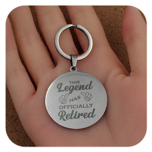 Silver keychain with 'This Legend Has Officially Retired' text held in a hand.