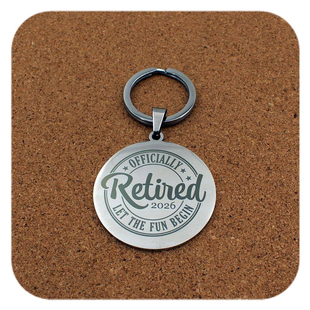 Silver keyring with Retired Let The Fun Begin 2026 design on cork background