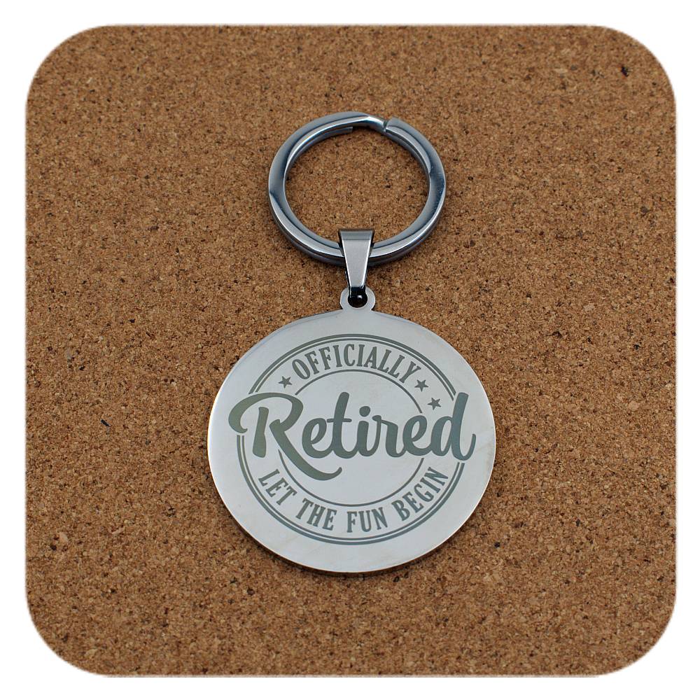 Keychain with 'Officially Retired, Let the Fun Begin' text on a cork background