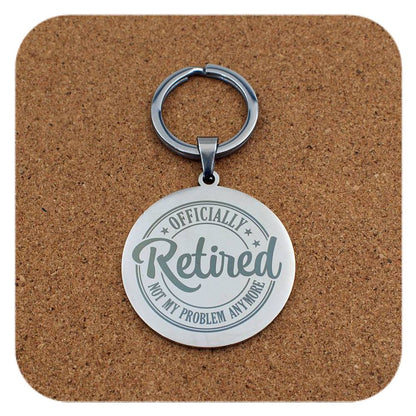 Keychain with 'Officially Retired, Not My Problem Anymore' text on a cork background