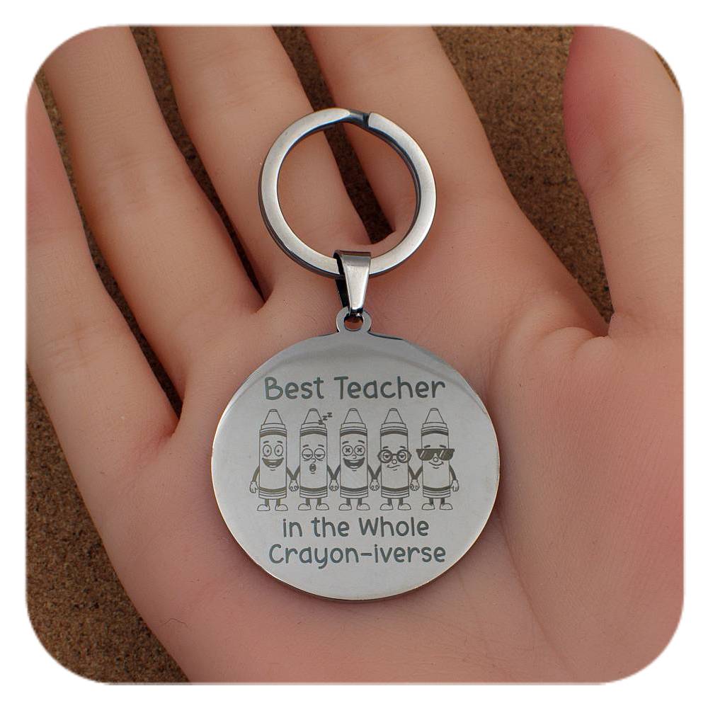 Silver keyring with Best Teacher In Crayon-iverse design held in a hand