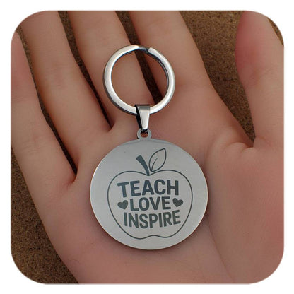 Silver keyring with Teach Love Inspire Apple design held in a hand