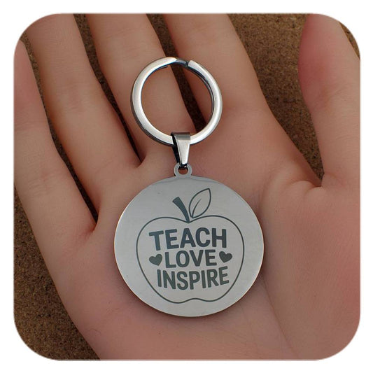Silver keyring with Teach Love Inspire Apple design held in a hand