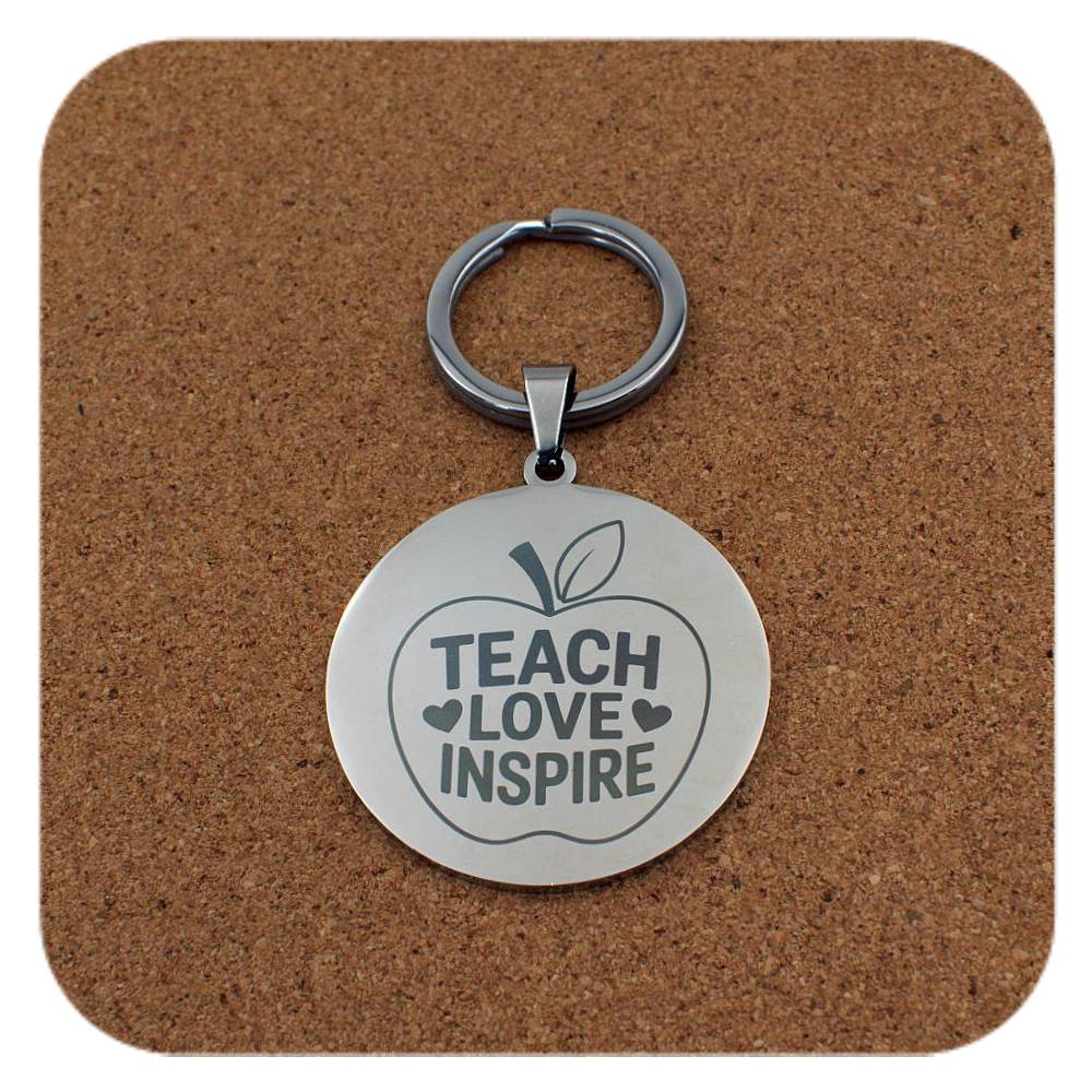 Silver keyring with Teach Love Inspire Apple design on cork background