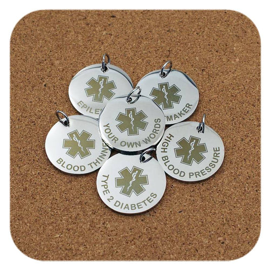 Silver pendants with different Star Of Life Emergency ID designs on cork background