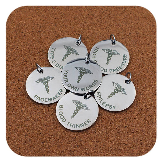 Silver pendants with different Caduceus Symbol Emergency ID designs on cork background