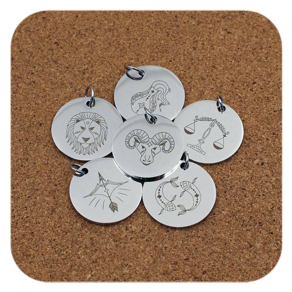 Silver pendants with different Zodiac Star Sign designs on cork background
