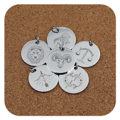 Silver pendants with different Zodiac Star Sign designs on cork background
