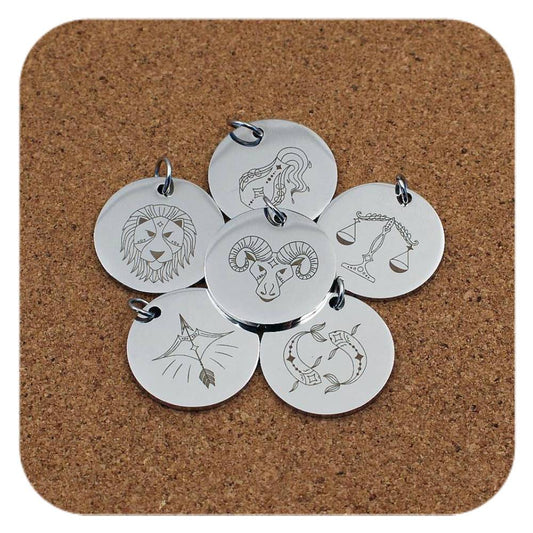 Silver pendants with different Zodiac Star Sign designs on cork background