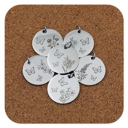 Silver pendants with different Birth Flower Butterfly designs on cork background