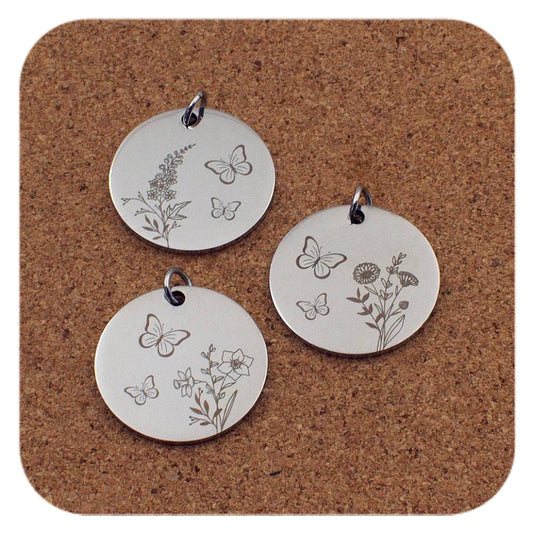 Silver pendants with different Birth Flower Butterfly designs on cork background