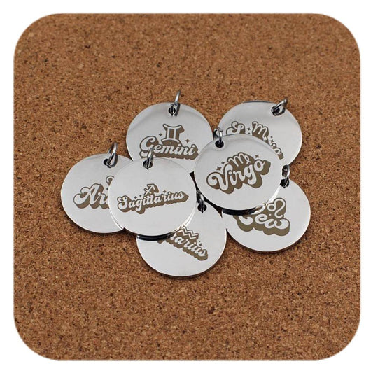 Silver pendants with different Zodiac Star Sign Words designs on cork background
