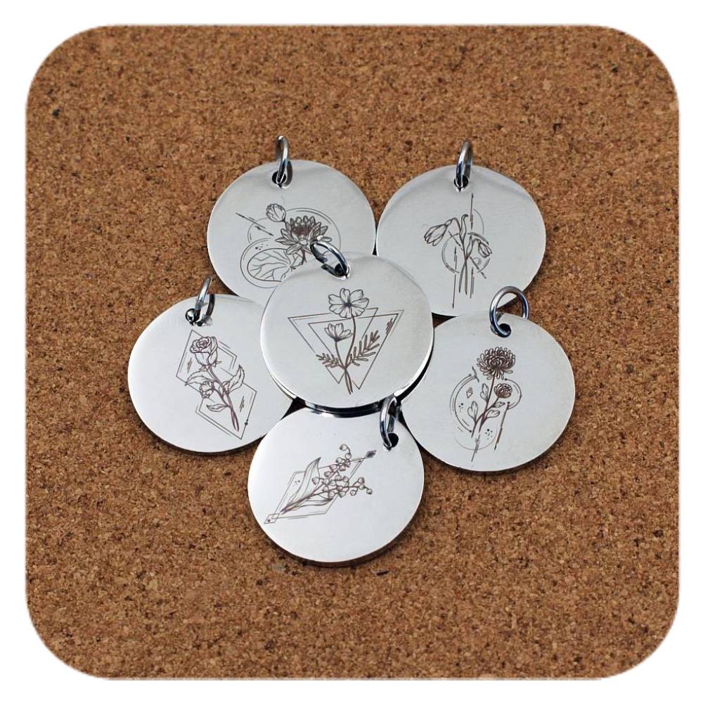 Silver pendants with different Geometric Birth Flower designs on cork background