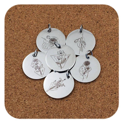Silver pendants with different Geometric Birth Flower designs on cork background