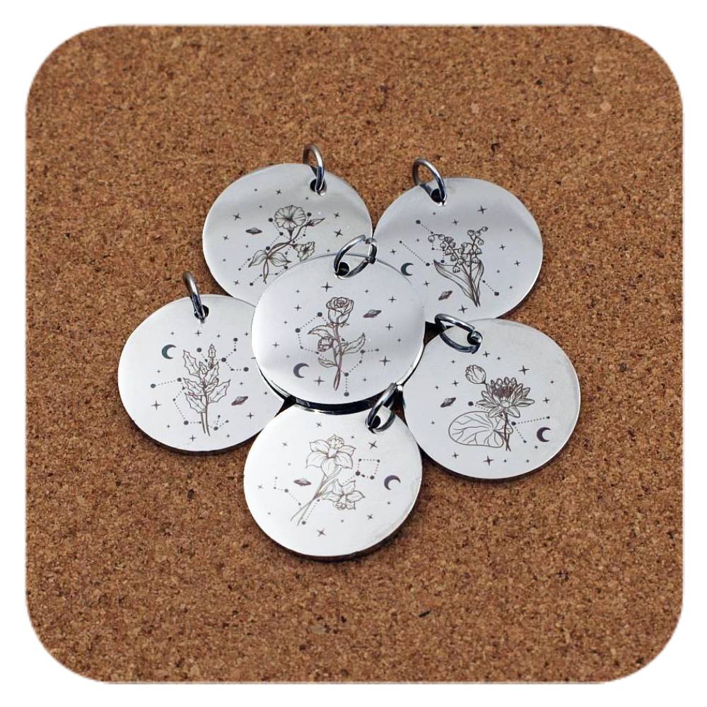 Silver pendants with different Celestial Birth Flower designs on cork background