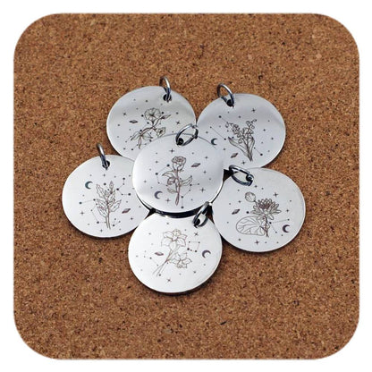 Silver pendants with different Celestial Birth Flower designs on cork background