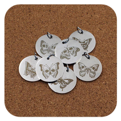 Silver pendants with different Skull And Butterfly Fusion designs on cork background