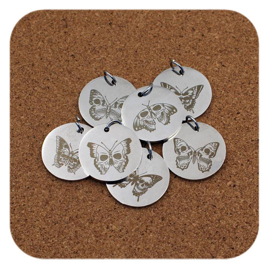 Silver pendants with different Skull And Butterfly Fusion designs on cork background