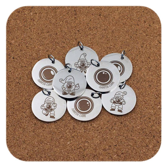 Silver pendants with different North Pole Santa Cam designs on cork background