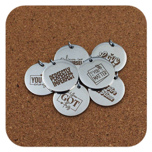 Silver pendants with different Inspirational designs on cork background