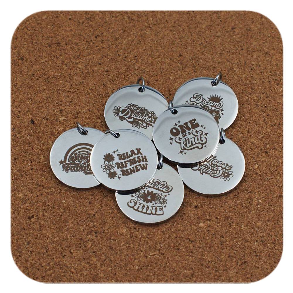 Silver pendants with different Inspiring Words designs on cork background