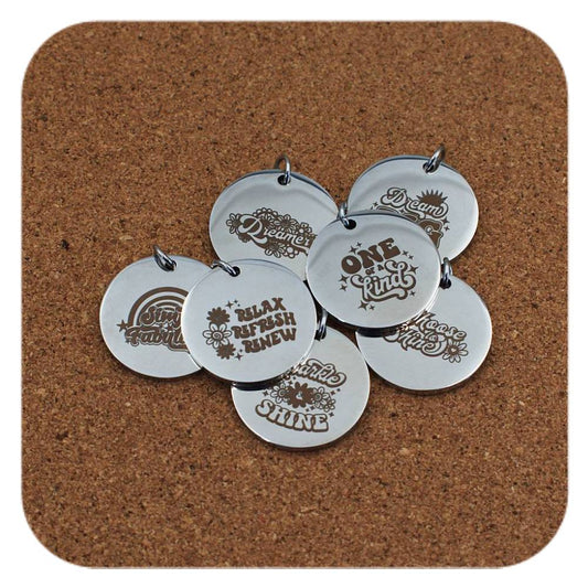 Silver pendants with different Inspiring Words designs on cork background