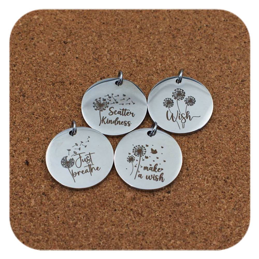 Silver pendants with different Uplifting Dandelion designs on cork background