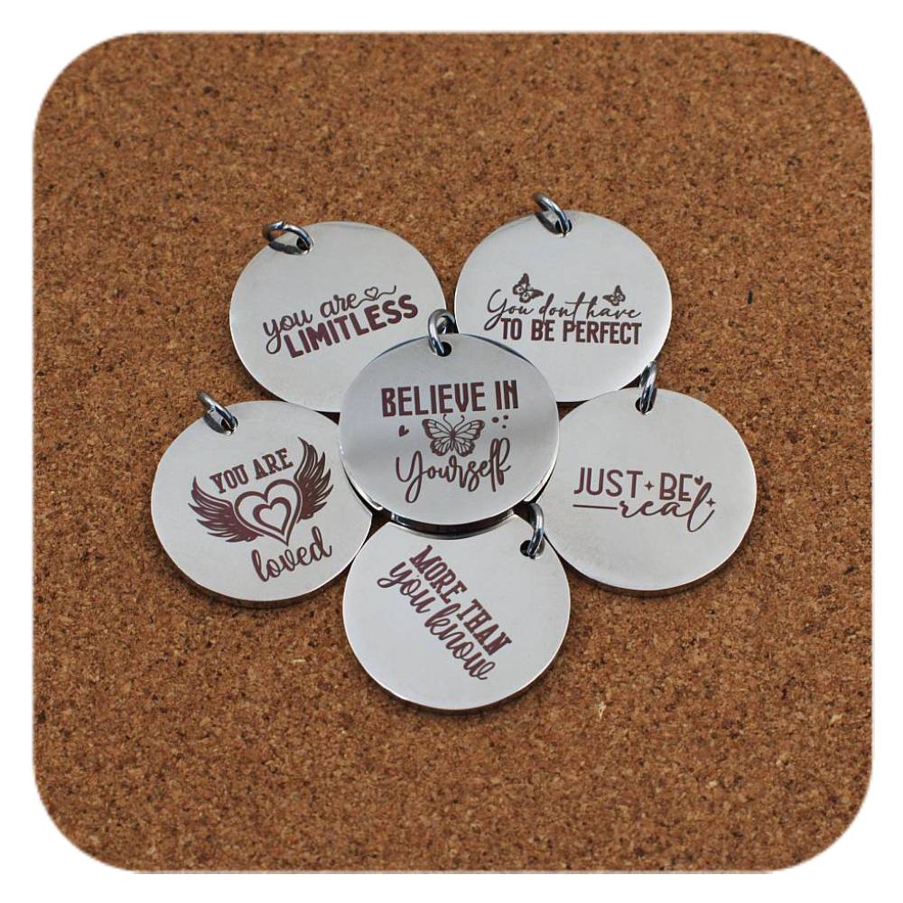 Silver pendants with different Positivity Quote designs on cork background