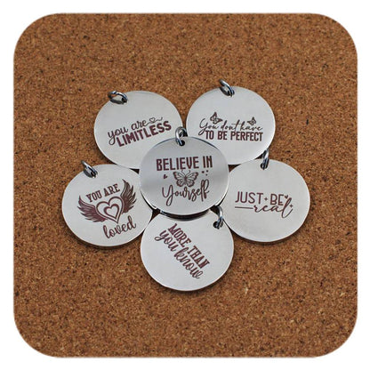 Silver pendants with different Positivity Quote designs on cork background