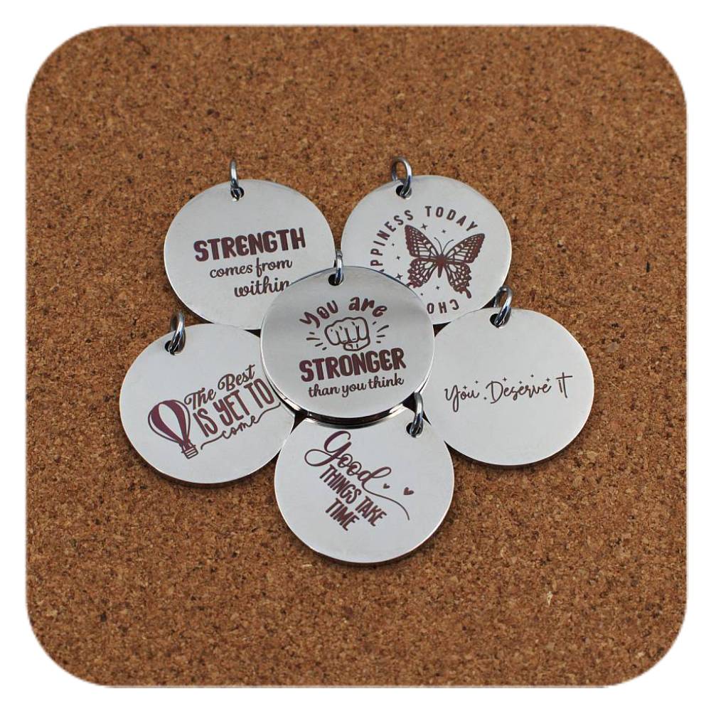 Silver pendants with different Positive Energy designs on cork background