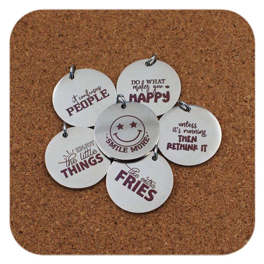 Silver pendants with different Smiles & Motivation designs on cork background