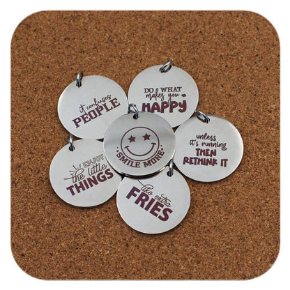 Silver pendants with different Smiles & Motivation designs on cork background